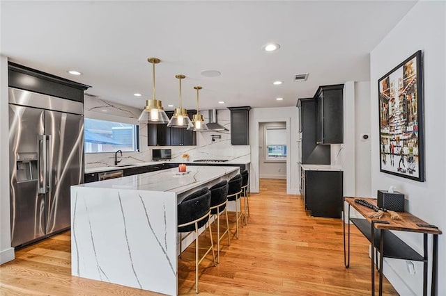 231 Audubon Blvd, New Orleans, LA 70125 - kitchen with high end refrigerator, a sink, wall chimney range hood, backsplash, and light wood-style flooring