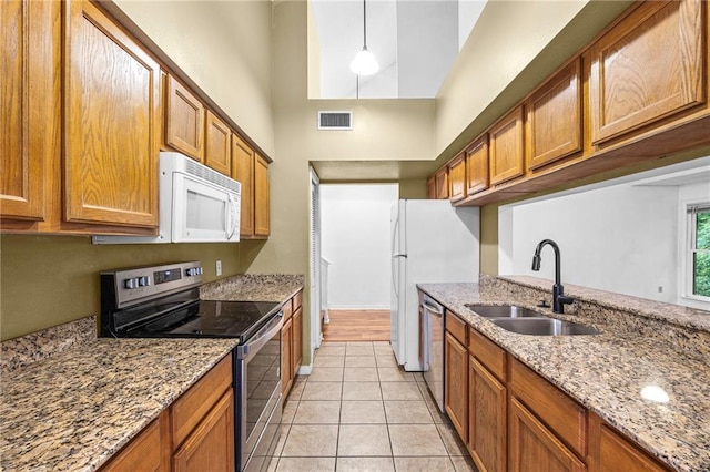 42 E Chamale Cv Unit 42, Slidell, LA 70460 - kitchen featuring stainless steel appliances, a sink, a high ceiling, brown cabinets, and light tile patterned floors