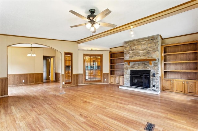 12175 Reid Rd, Amite, LA 70422 - unfurnished living room featuring wainscoting, light wood-type flooring, crown molding, a stone fireplace, and ceiling fan