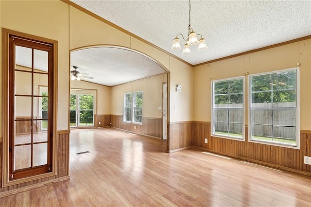 12175 Reid Rd, Amite, LA 70422 - spare room with a textured ceiling, wood finished floors, arched walkways, a chandelier, and a wainscoted wall