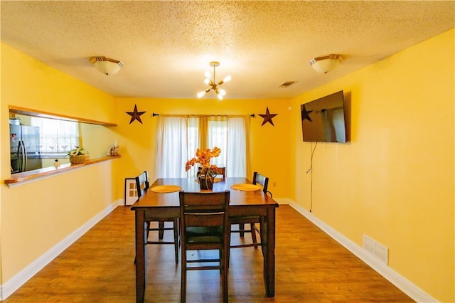 2404 Timbers Dr, Harvey, LA 70058 - dining room featuring a textured ceiling, a chandelier, wood finished floors, and baseboards