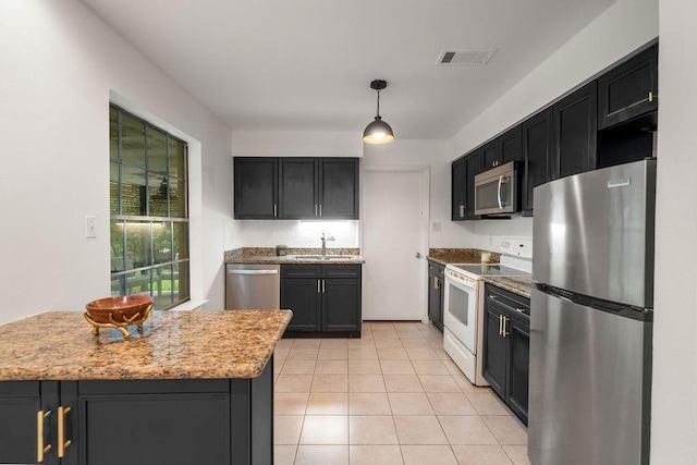 71164 Clipper Pl, Abita Springs, LA 70420 - kitchen with stainless steel appliances, a sink, light tile patterned flooring, and dark cabinets