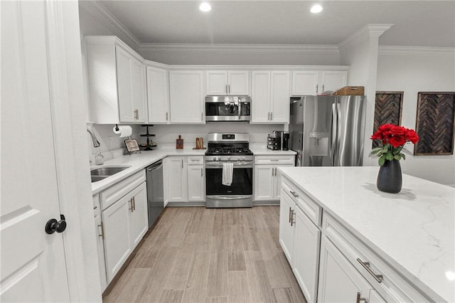 39593 Fly Creek Rd, Ponchatoula, LA 70454 - kitchen featuring appliances with stainless steel finishes, a sink, white cabinetry, crown molding, and light wood finished floors