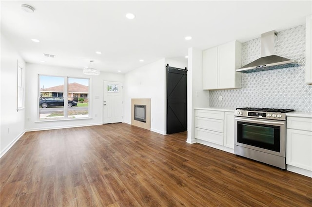 1221 Gaudet Dr, Marrero, LA 70072 - kitchen featuring wall chimney range hood, gas range, a barn door, dark wood finished floors, and white cabinetry