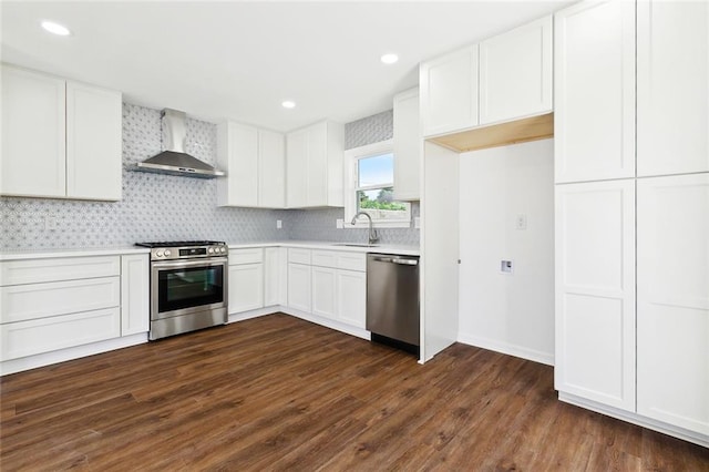 1221 Gaudet Dr, Marrero, LA 70072 - kitchen featuring wall chimney range hood, appliances with stainless steel finishes, dark wood-type flooring, light countertops, and white cabinetry