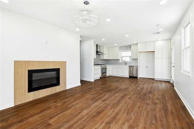 1221 Gaudet Dr, Marrero, LA 70072 - unfurnished living room with dark wood-type flooring, a chandelier, recessed lighting, and a glass covered fireplace