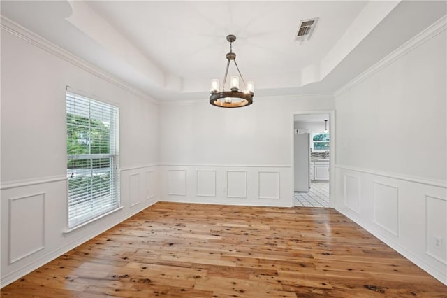 310 Scotchpine Dr, Mandeville, LA 70471 - spare room with a chandelier, a raised ceiling, light wood-type flooring, a wainscoted wall, and a decorative wall