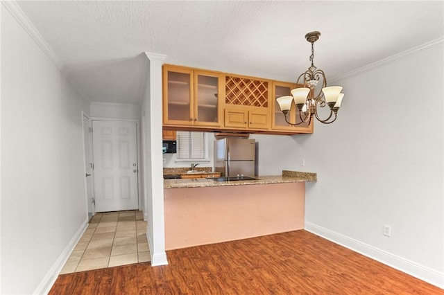 3805 Houma Blvd Unit C101, Metairie, LA 70006 - kitchen with freestanding refrigerator, glass insert cabinets, wood finished floors, crown molding, and black microwave