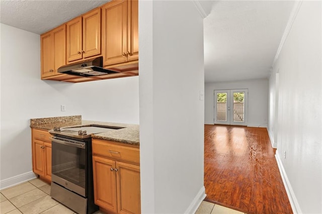 3805 Houma Blvd Unit C101, Metairie, LA 70006 - kitchen featuring stainless steel electric range oven, under cabinet range hood, stone counters, baseboards, and light wood-type flooring