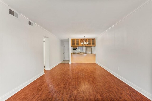 3805 Houma Blvd Unit C101, Metairie, LA 70006 - unfurnished living room featuring a chandelier, wood finished floors, crown molding, and baseboards