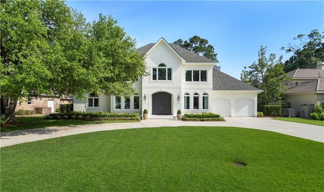 139 Fontainbleau Dr, Mandeville, LA 70471 - french country style house with concrete driveway, a front yard, a garage, stucco siding, and roof with shingles