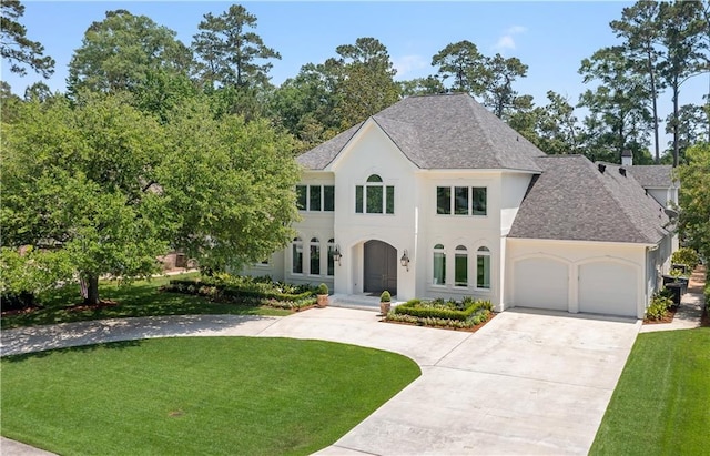139 Fontainbleau Dr, Mandeville, LA 70471 - french country home featuring roof with shingles, an attached garage, concrete driveway, and stucco siding