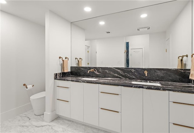 139 Fontainbleau Dr, Mandeville, LA 70471 - bathroom featuring marble look tile flooring, toilet, double vanity, recessed lighting, and baseboards