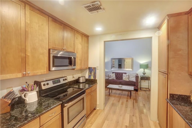 723 Kerlerec St, New Orleans, LA 70116 - kitchen with appliances with stainless steel finishes, light wood finished floors, and dark stone countertops