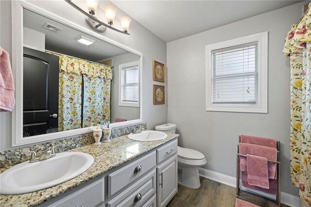285 8th Street Dr, Ponchatoula, LA 70454 - bathroom featuring double vanity, toilet, wood finished floors, baseboards, and a shower with shower curtain