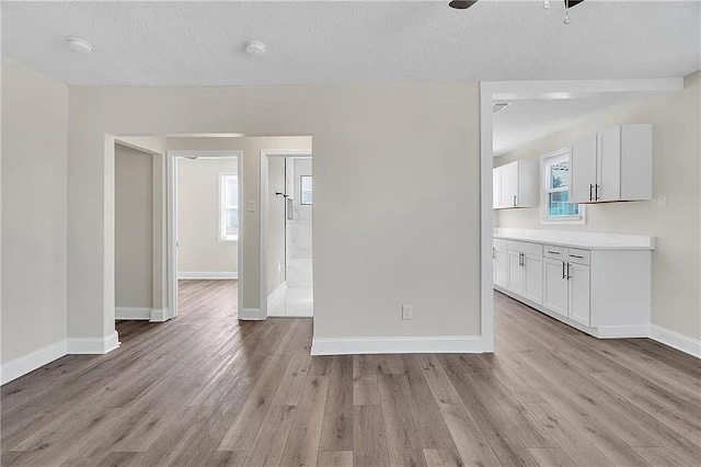 6073 Wickfield Dr, New Orleans, LA 70122 - unfurnished living room featuring light wood-style flooring, a ceiling fan, baseboards, and a textured ceiling