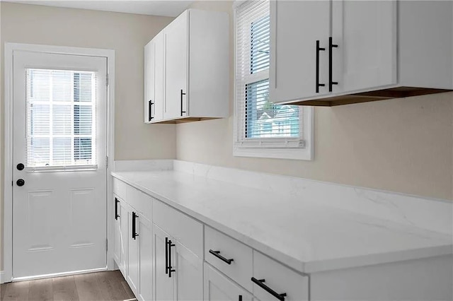 6073 Wickfield Dr, New Orleans, LA 70122 - kitchen featuring white cabinetry, light stone countertops, and light wood-style flooring