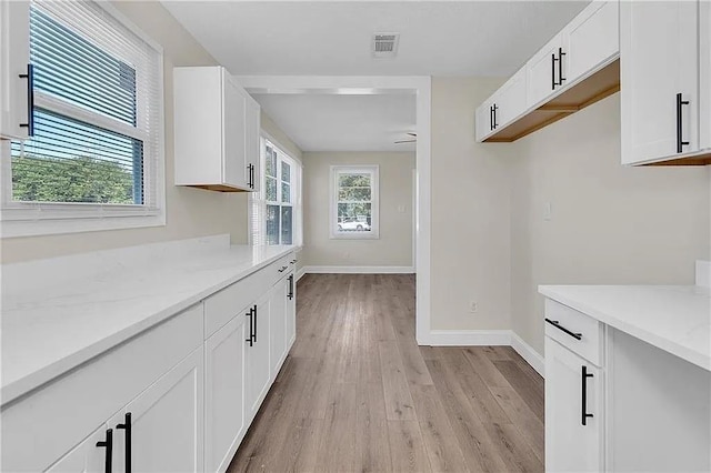 6073 Wickfield Dr, New Orleans, LA 70122 - kitchen with light wood-style flooring, baseboards, and white cabinets