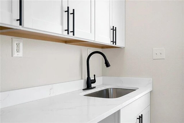 6073 Wickfield Dr, New Orleans, LA 70122 - detailed view of a sink, white cabinetry, and light stone counters