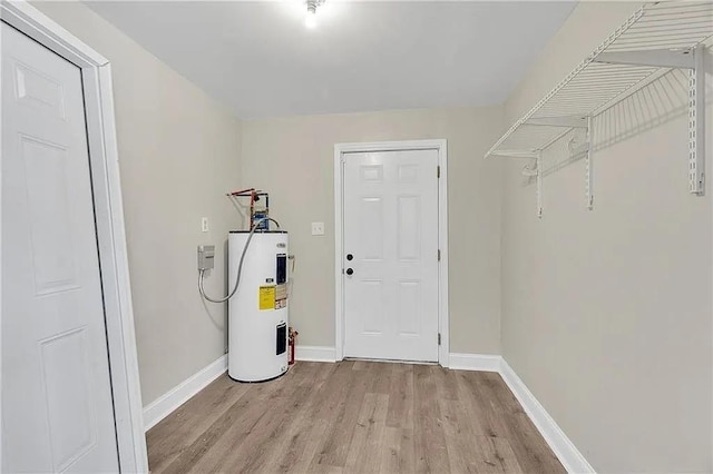 6073 Wickfield Dr, New Orleans, LA 70122 - washroom featuring electric water heater, light wood-style floors, and baseboards