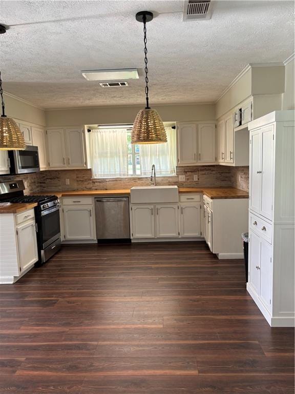 11036 Gulino Rd, Amite, LA 70422 - kitchen with appliances with stainless steel finishes, a sink, a textured ceiling, dark wood-style flooring, and tasteful backsplash