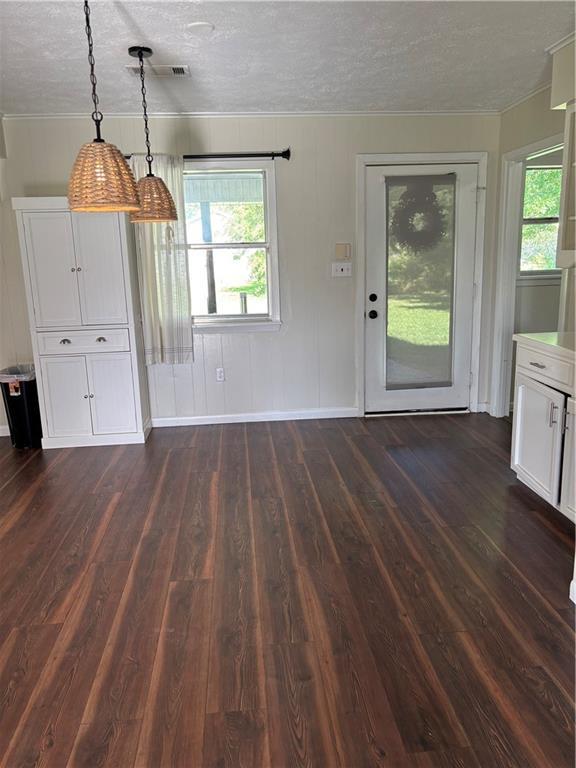 11036 Gulino Rd, Amite, LA 70422 - unfurnished dining area featuring a textured ceiling, crown molding, dark wood-type flooring, plenty of natural light, and baseboards