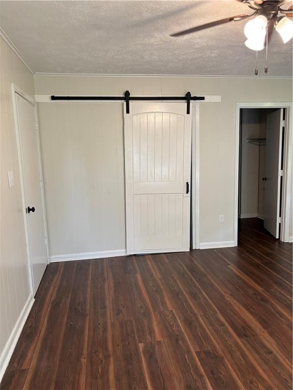 11036 Gulino Rd, Amite, LA 70422 - unfurnished bedroom featuring a barn door, crown molding, a textured ceiling, wood finished floors, and baseboards