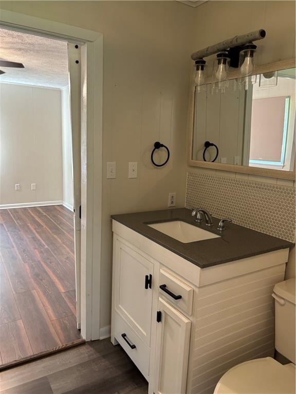 11036 Gulino Rd, Amite, LA 70422 - bathroom featuring wood finished floors, vanity, toilet, and backsplash