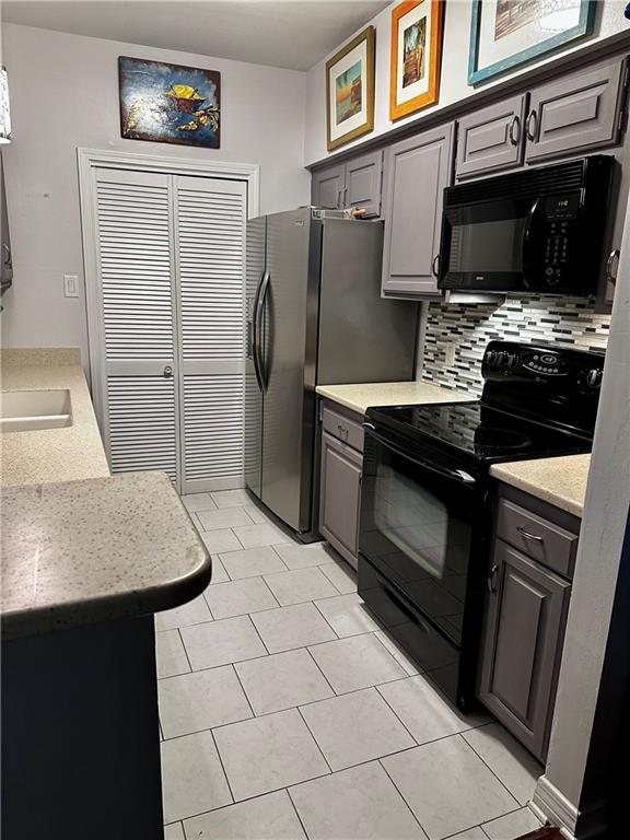 3514 Audubon Trce Unit 3514, Jefferson, LA 70121 - kitchen featuring black appliances, backsplash, light countertops, gray cabinetry, and light tile patterned floors