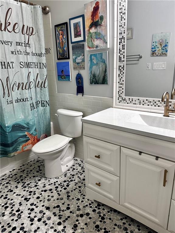 3514 Audubon Trce Unit 3514, Jefferson, LA 70121 - full bath featuring vanity, tile walls, toilet, a shower with curtain, and wainscoting