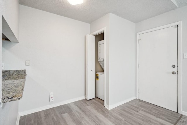 4218 Hessmer Ave Unit 309, Metairie, LA 70002 - foyer entrance featuring stacked washer / dryer, light wood finished floors, a textured ceiling, and baseboards