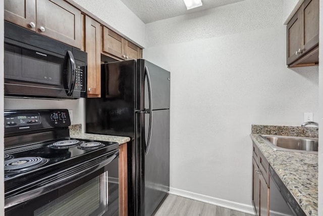 4218 Hessmer Ave Unit 309, Metairie, LA 70002 - kitchen with black appliances, a sink, light wood-type flooring, light stone countertops, and baseboards
