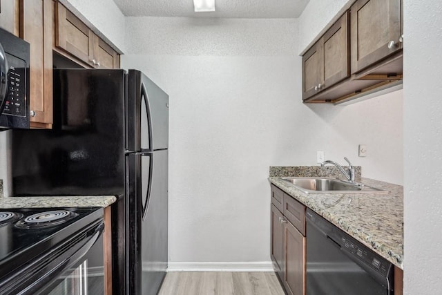 4218 Hessmer Ave Unit 309, Metairie, LA 70002 - kitchen featuring a sink, black appliances, light wood-style floors, baseboards, and light stone countertops