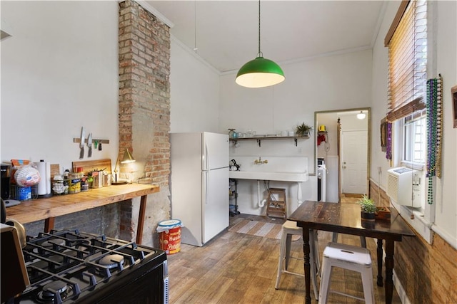 210911 Josephine St, New Orleans, LA 70113 - kitchen featuring freestanding refrigerator, a towering ceiling, ornamental molding, wood finished floors, and gas stove