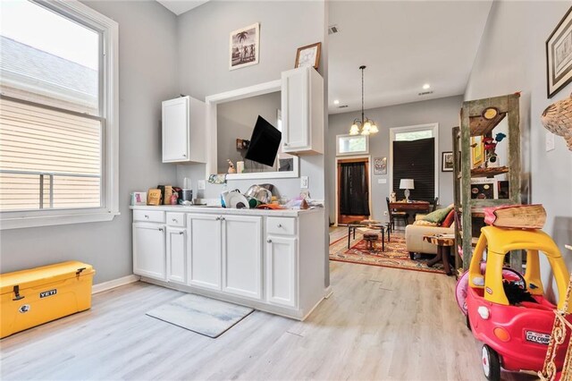 4716-18 Burgundy St, New Orleans, LA 70117 - kitchen featuring light wood-type flooring, white cabinets, light countertops, a chandelier, and baseboards