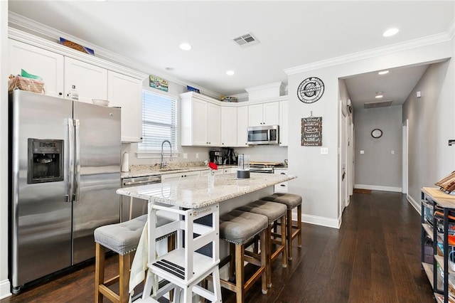 1233 Brockenbraugh Ct, Metairie, LA 70005 - kitchen featuring appliances with stainless steel finishes, crown molding, a breakfast bar area, white cabinetry, and a sink