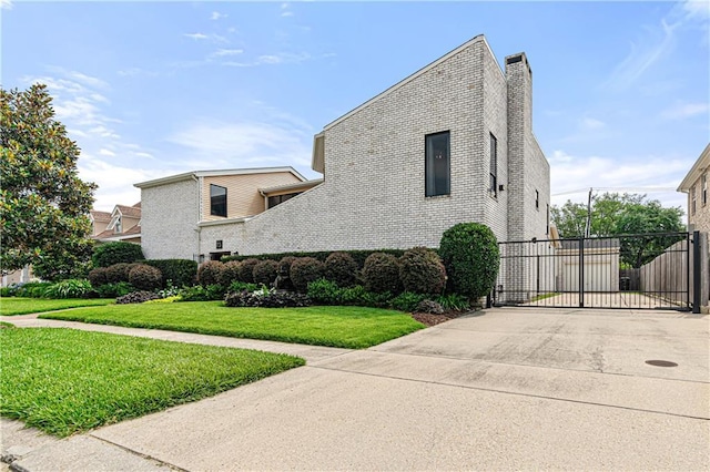 73 Doescher Dr, Harahan, LA 70123 - view of side of property featuring a gate, a chimney, brick siding, and concrete driveway