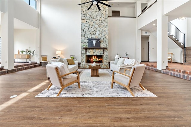 73 Doescher Dr, Harahan, LA 70123 - living room featuring a high ceiling, ceiling fan, wood finished floors, a stone fireplace, and stairs