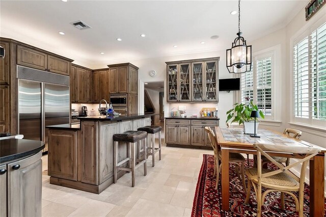 105 Mulberry Dr, Metairie, LA 70005 - kitchen featuring built in fridge, dark countertops, oven, a breakfast bar area, and a center island with sink