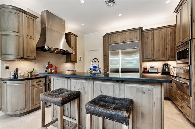 105 Mulberry Dr, Metairie, LA 70005 - kitchen with wall chimney exhaust hood, built in appliances, a warming drawer, dark countertops, and tasteful backsplash