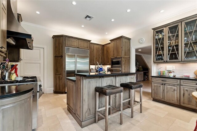 105 Mulberry Dr, Metairie, LA 70005 - kitchen with built in appliances, dark countertops, a breakfast bar, wall chimney range hood, and recessed lighting