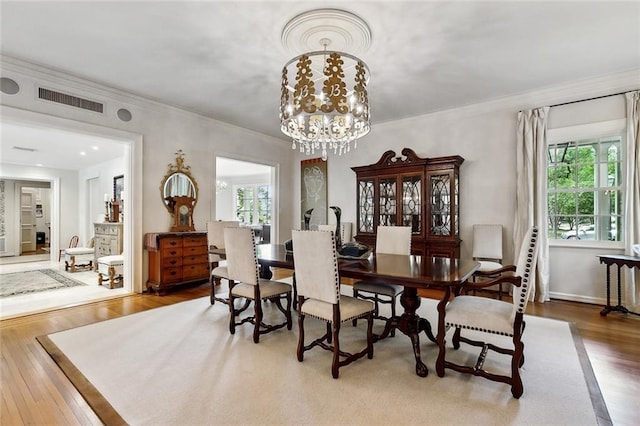 105 Mulberry Dr, Metairie, LA 70005 - dining room with healthy amount of natural light, ornamental molding, wood finished floors, and a chandelier