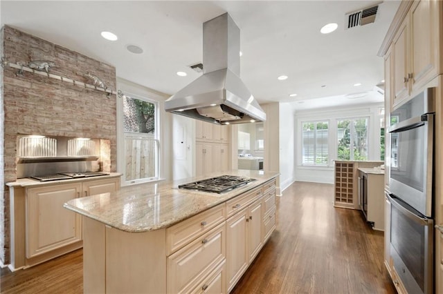 1923 State St, New Orleans, LA 70118 - kitchen featuring island range hood, appliances with stainless steel finishes, wood finished floors, light stone counters, and a center island