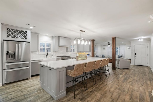 5844 Fleur De Lis Dr, New Orleans, LA 70124 - kitchen with stainless steel appliances, a ceiling fan, gray cabinetry, decorative backsplash, and wood finished floors