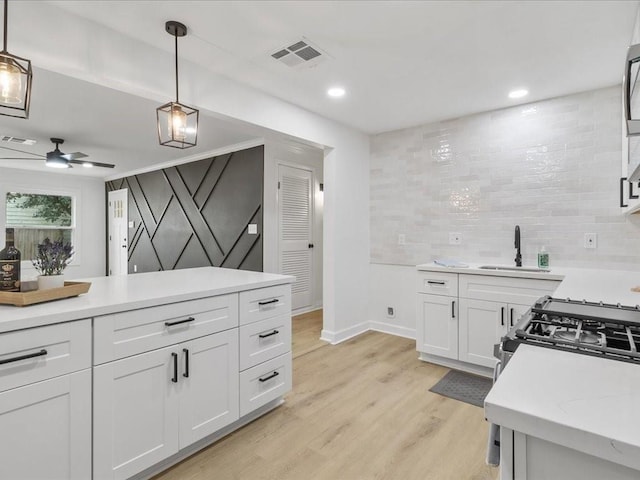 1705 Haring Rd, Metairie, LA 70001 - kitchen with a sink, white cabinets, hanging light fixtures, light wood-style floors, and baseboards