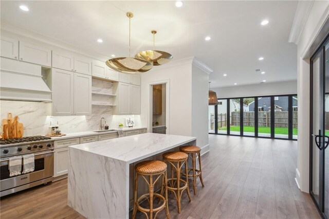1015 Cadiz St, New Orleans, LA 70115 - kitchen featuring high end range, recessed lighting, a kitchen island, backsplash, and light stone counters