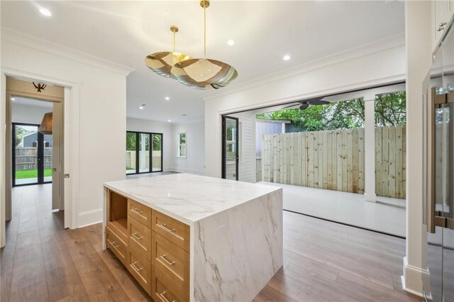 1015 Cadiz St, New Orleans, LA 70115 - kitchen featuring ornamental molding, wood finished floors, light stone counters, a kitchen island, and recessed lighting