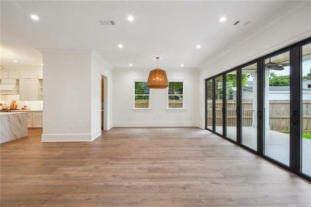 1015 Cadiz St, New Orleans, LA 70115 - unfurnished living room with plenty of natural light, crown molding, baseboards, light wood-style flooring, and recessed lighting