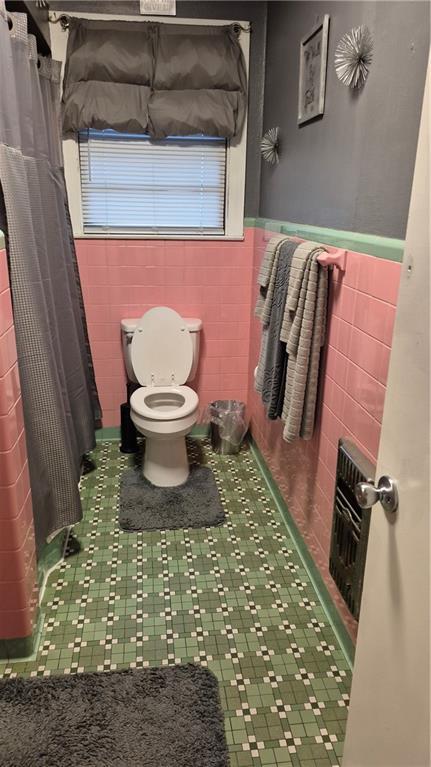 3218 Gentilly Blvd, New Orleans, LA 70122 - full bathroom with tile walls, toilet, wainscoting, and a shower with curtain