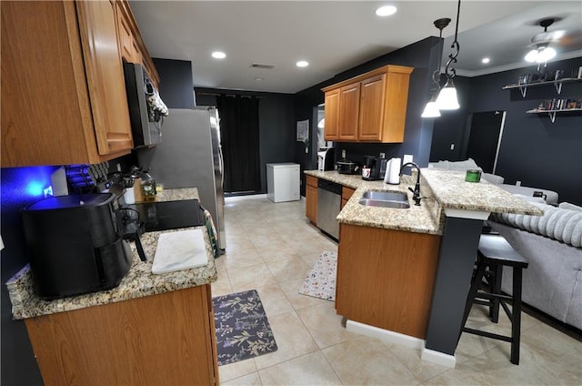 1613 Live Oak St, Slidell, LA 70460 - kitchen featuring appliances with stainless steel finishes, a peninsula, a kitchen breakfast bar, light stone countertops, and light tile patterned floors